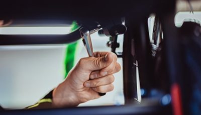 Hand führt Reparatur an einem Rollstuhl durch als Beispiel für Werkstattservice bei Saniplus Baunatal